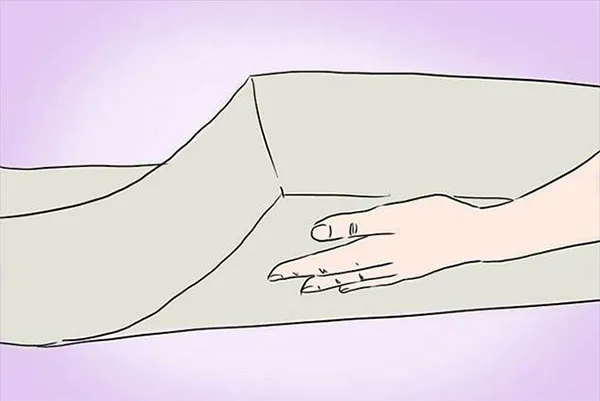 Een hand die in een matras wordt gedrukt om de dikte van de laag te beoordelen